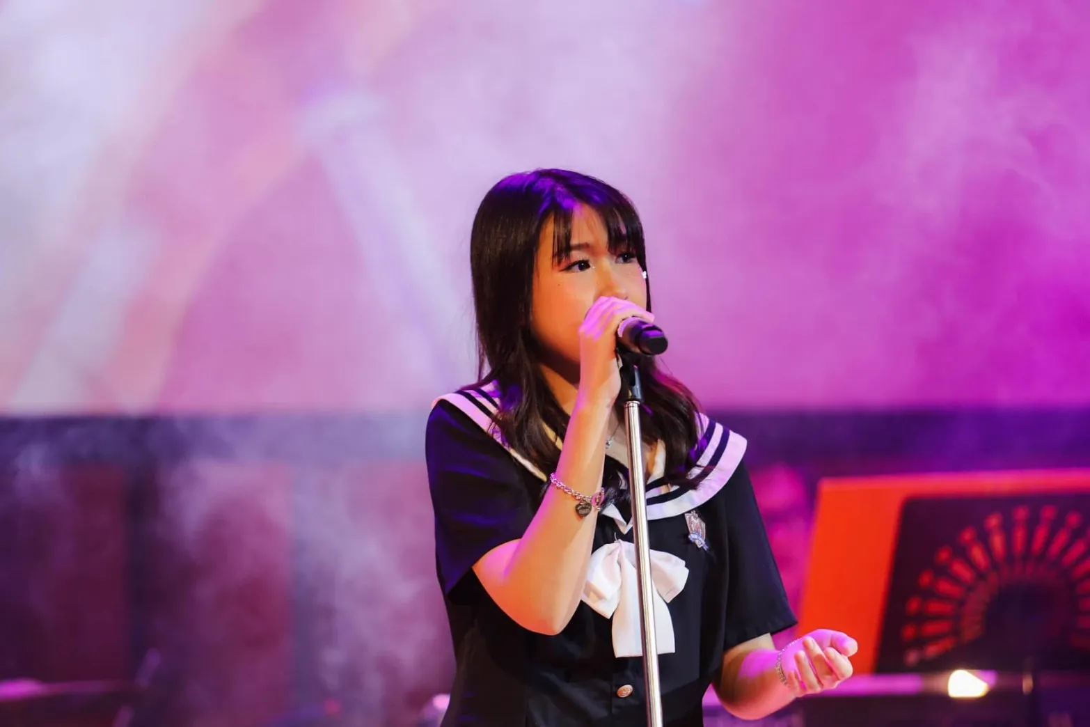 นักเรียนร้องเพลงบนเวทีภายใต้แสงไฟ