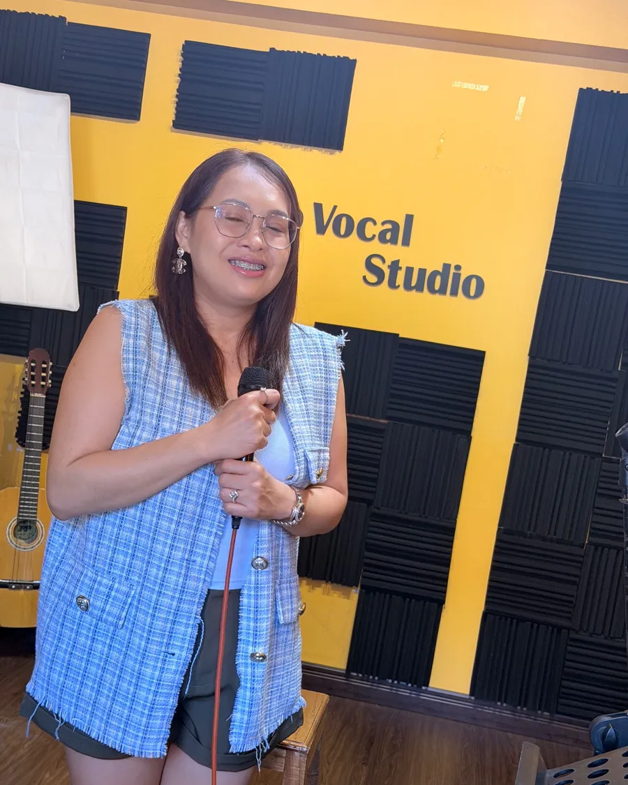นักเรียนผู้ใหญ่ฝึกร้องเพลงหน้าผนังสตูดิโอ Kru Po Vocal Studio